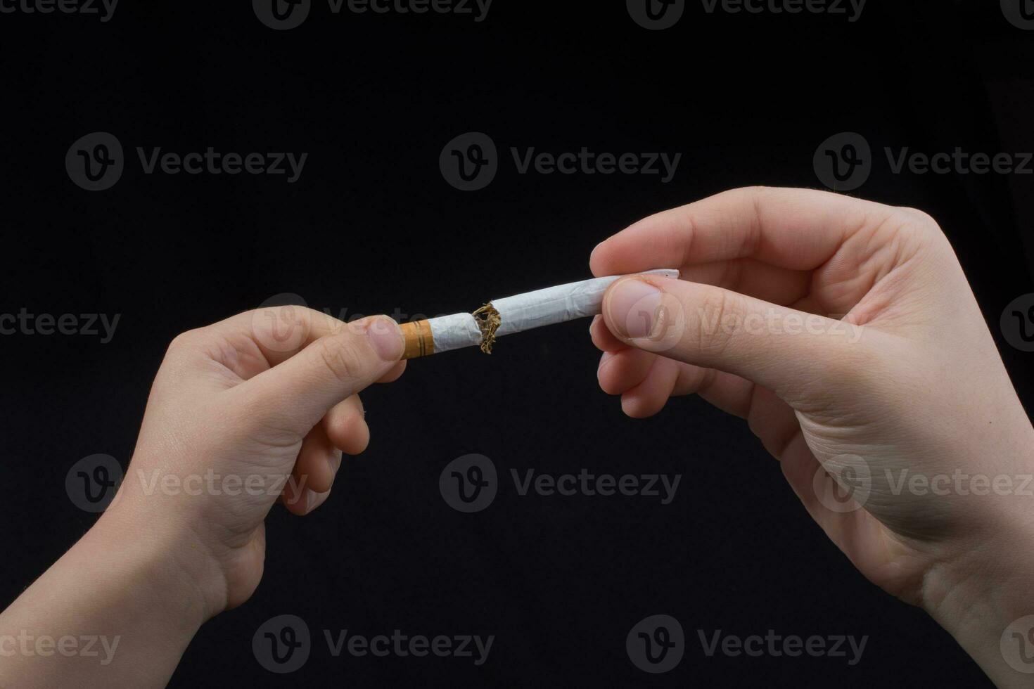 Hand is breaking a cigarette on black background photo