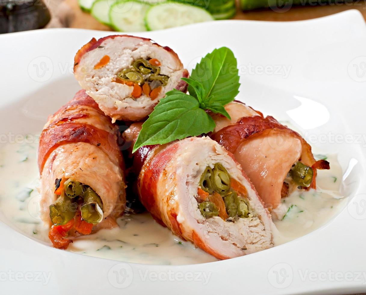 Delicious chicken rolls stuffed with green beans and carrots wrapped in strips of bacon photo