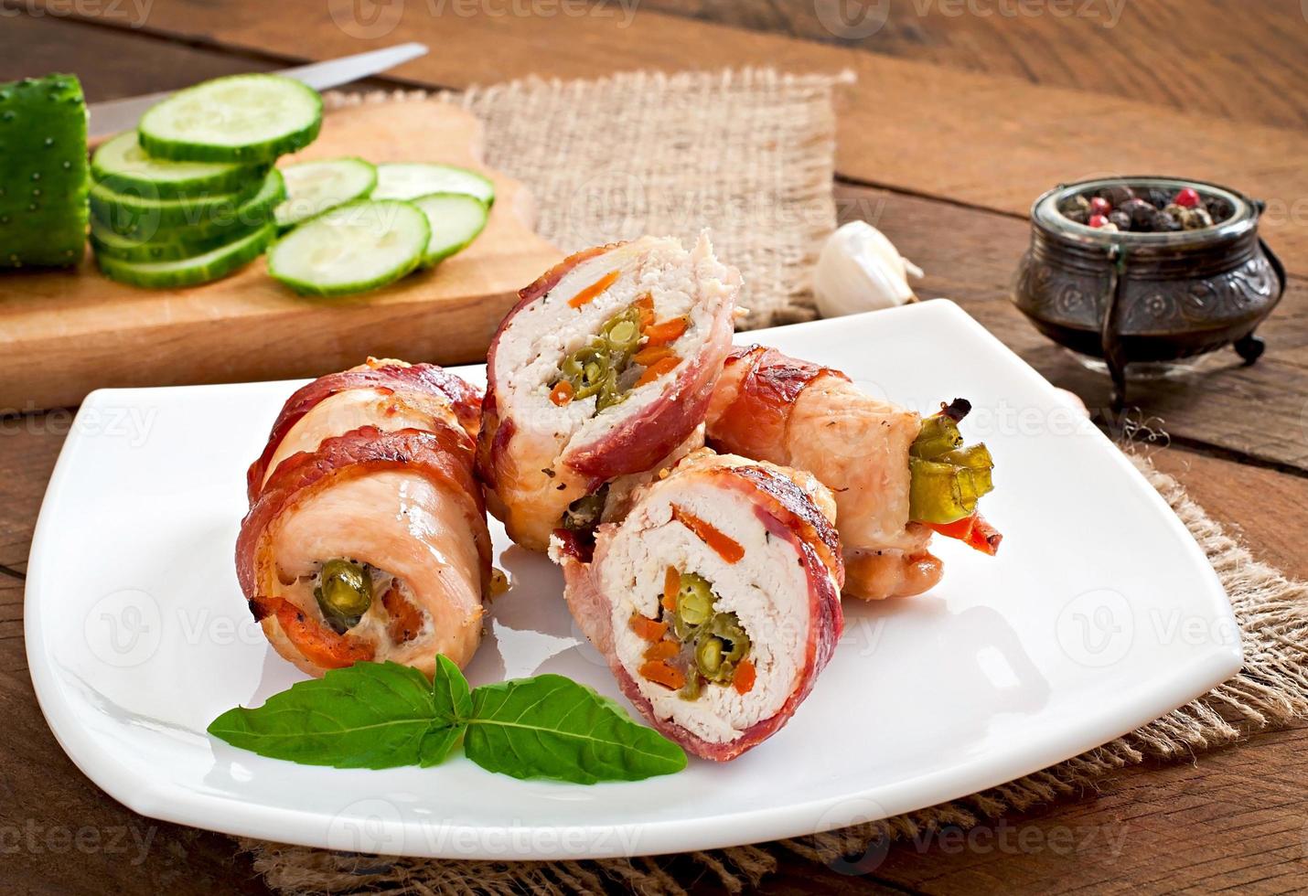 Delicious chicken rolls stuffed with green beans and carrots wrapped in strips of bacon photo