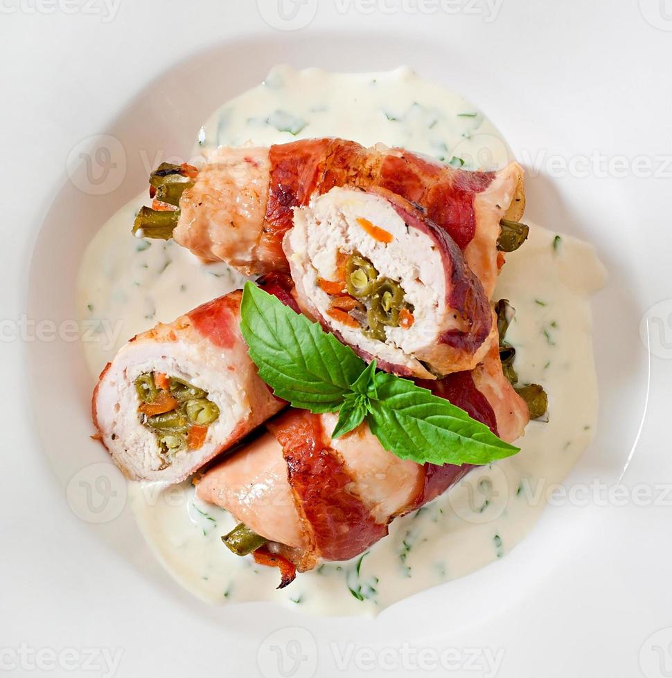Delicious chicken rolls stuffed with green beans and carrots wrapped in strips of bacon photo