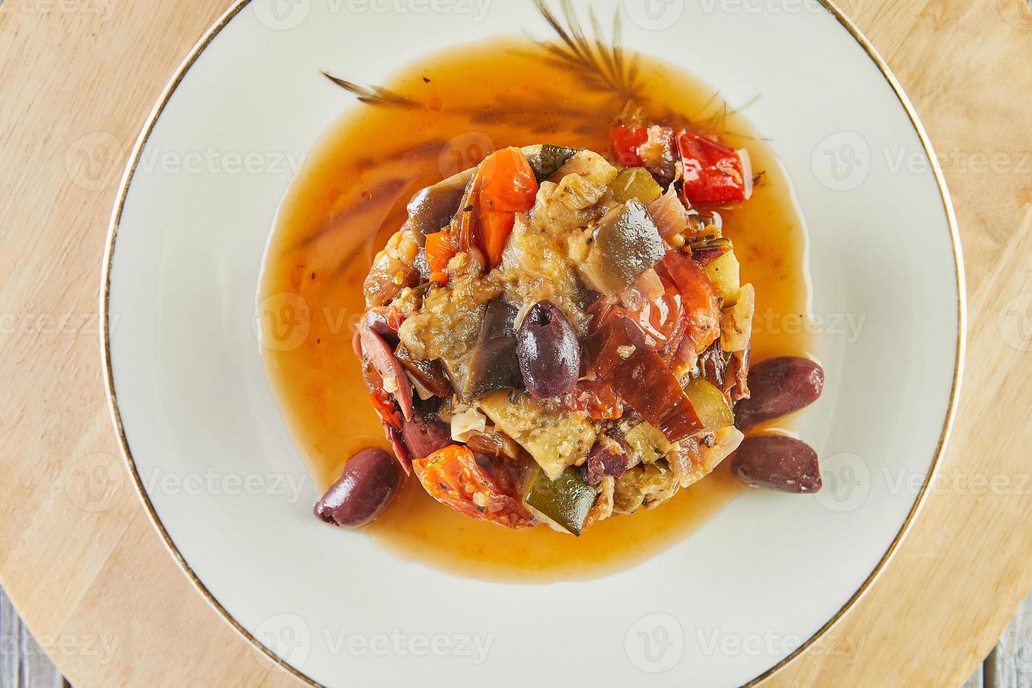 ragú de ratatouille con calabacín, calabacín, berenjena, pimientos y tomates cherry. decorado con aceitunas. cocina gourmet francesa foto