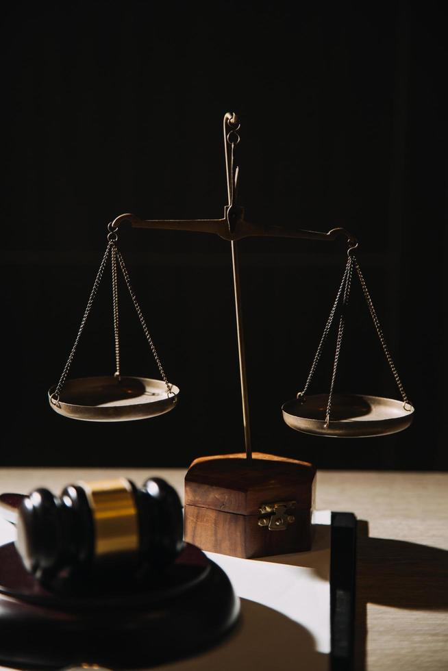 Justice and law concept.Male judge in a courtroom with the gavel, working with, computer and docking keyboard, eyeglasses, on table in morning light photo