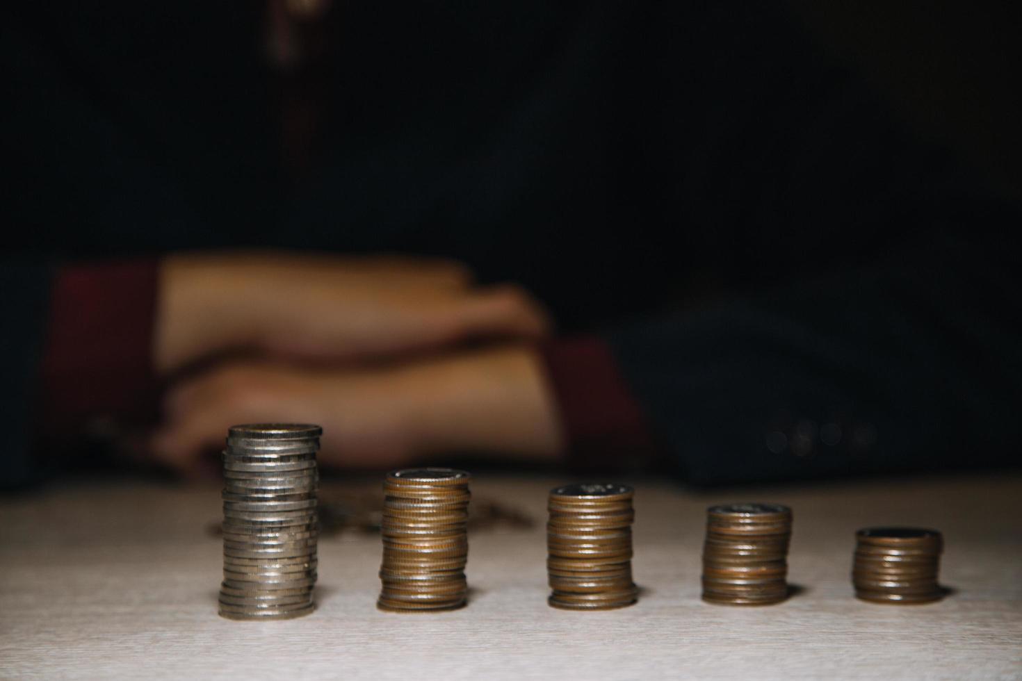 ahorrar dinero a mano poniendo monedas en la pila en la mesa con sol. concepto finanzas y contabilidad foto