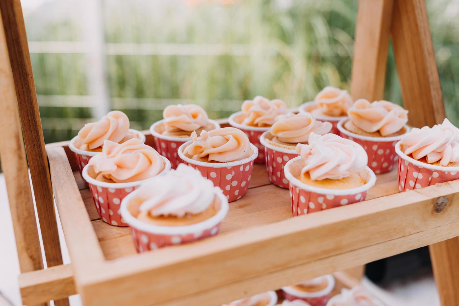 Gourmet cupcakes with white buttercream frosting and sprinkles on wooden background photo