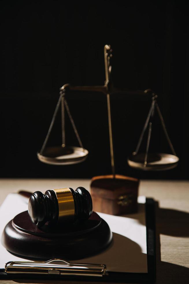 Justice and law concept.Male judge in a courtroom with the gavel, working with, computer and docking keyboard, eyeglasses, on table in morning light photo