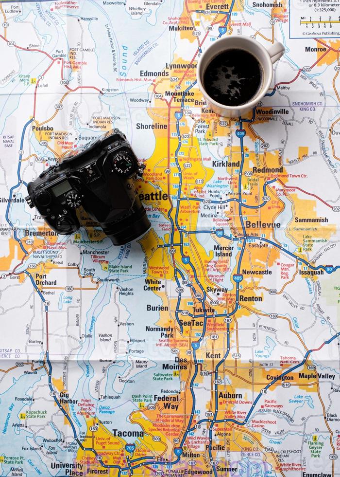 Flat lay traveler accessories on map, camera and cup of coffee photo