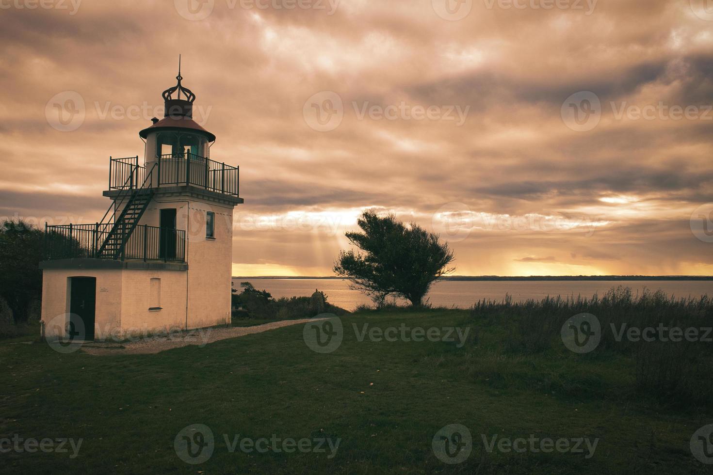 Lighthouse, Spodsbjerg Fyr in Huntsted on the coast of Denmark. Sun rays shining photo