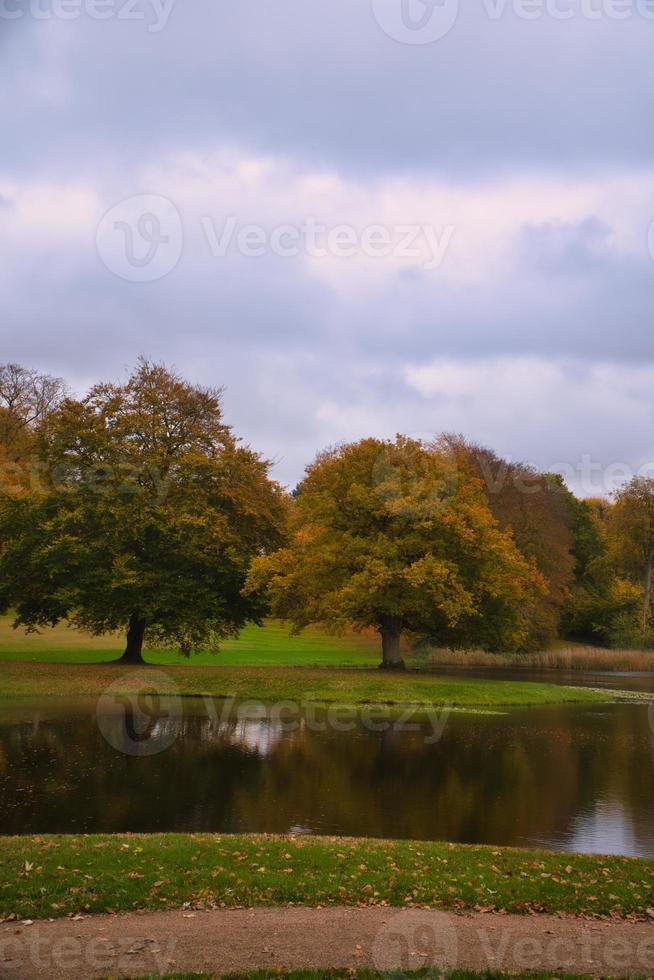 parque del castillo de frederiksborg con poderosos árboles de hoja caduca, reflejados en el lago creado. foto