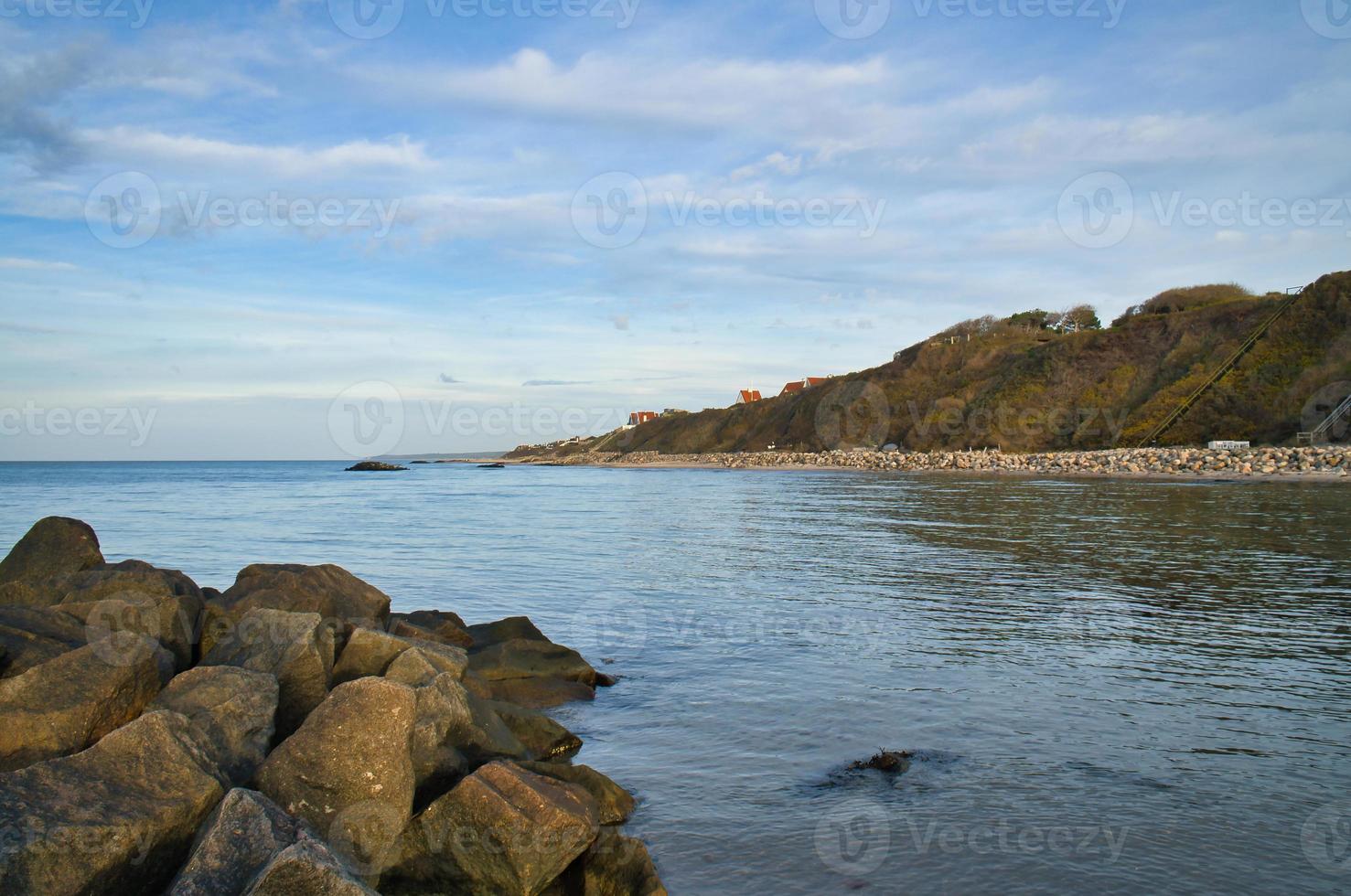 Stone groyne jutting into sea in Denmark with clouds in sky. Coastal landscape in Denmark. Landscape photo from ocean