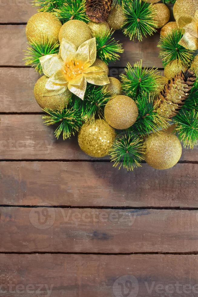 Shiny yellow Christmas balls and cone with barks and pine branches on brown wooden boards background. New year card photo