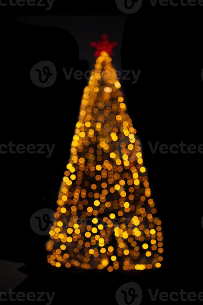 Blurred yellow Christmas tree lights on black isolated background. Design element. Defocused spruce with star. Overlay. New Year photo