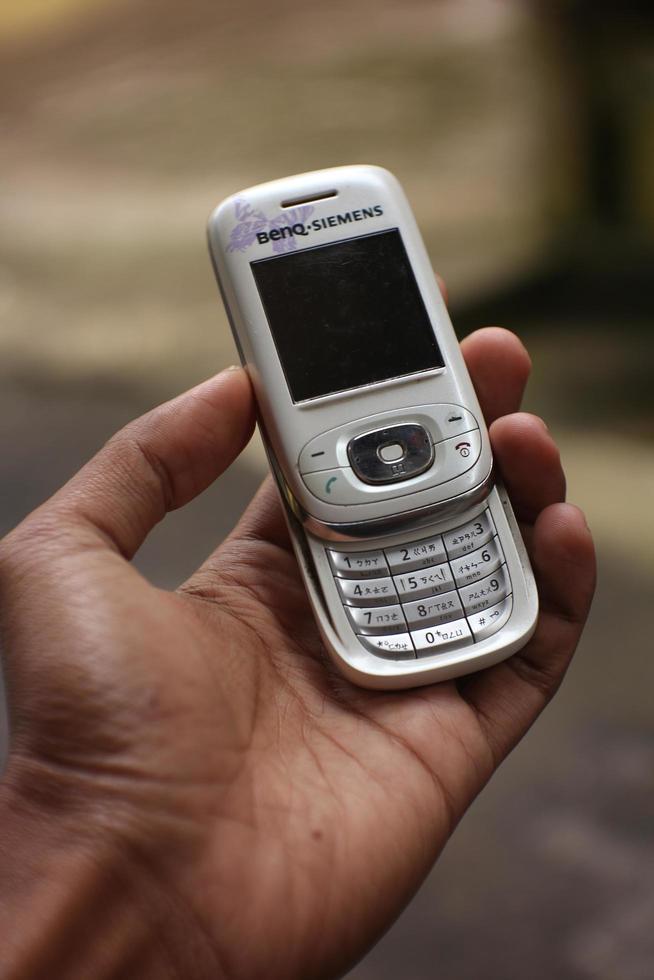 Magelang,Indonesia,2022-hand holding an ancient white cell phone not yet an android version. photo