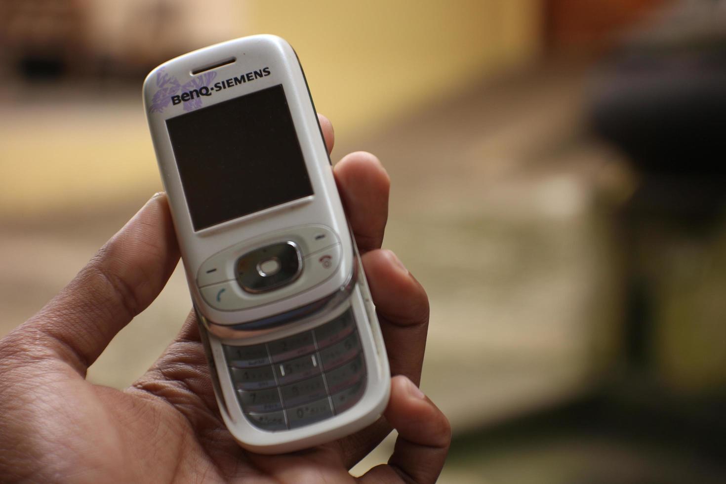 magelang, indonesia, 2022-mano sosteniendo un antiguo teléfono celular blanco que aún no es una versión de Android. foto