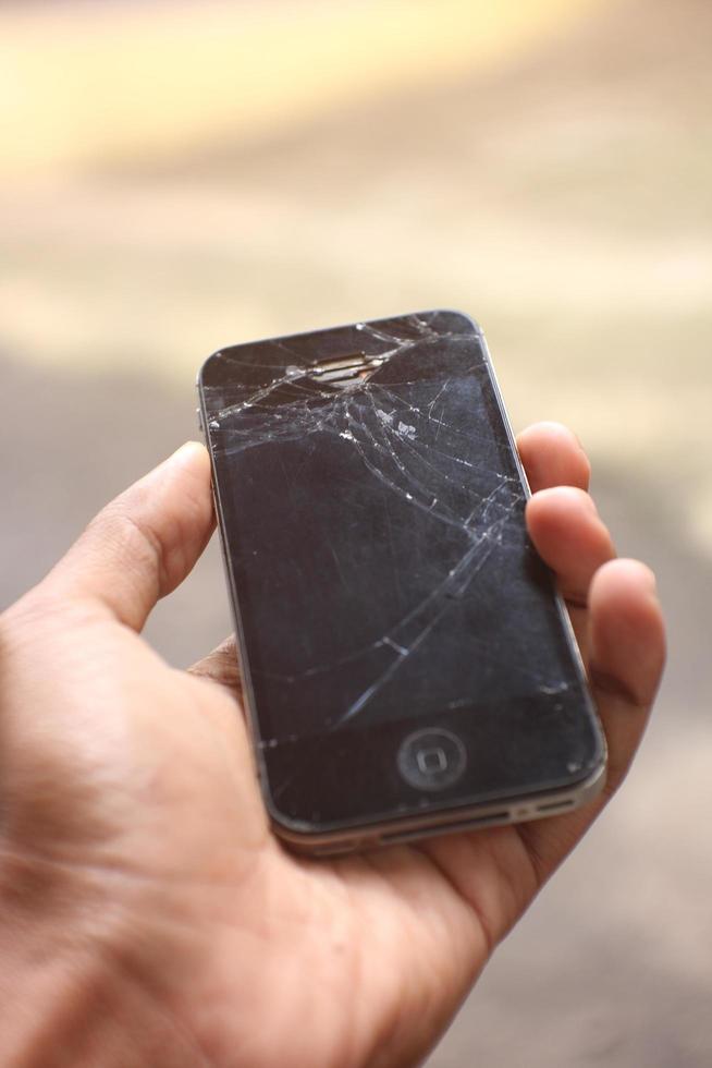 Magelang,Indonesia,2022-human hand holds smartphone iPhone 4s of black color with accidentally broken glass. photo