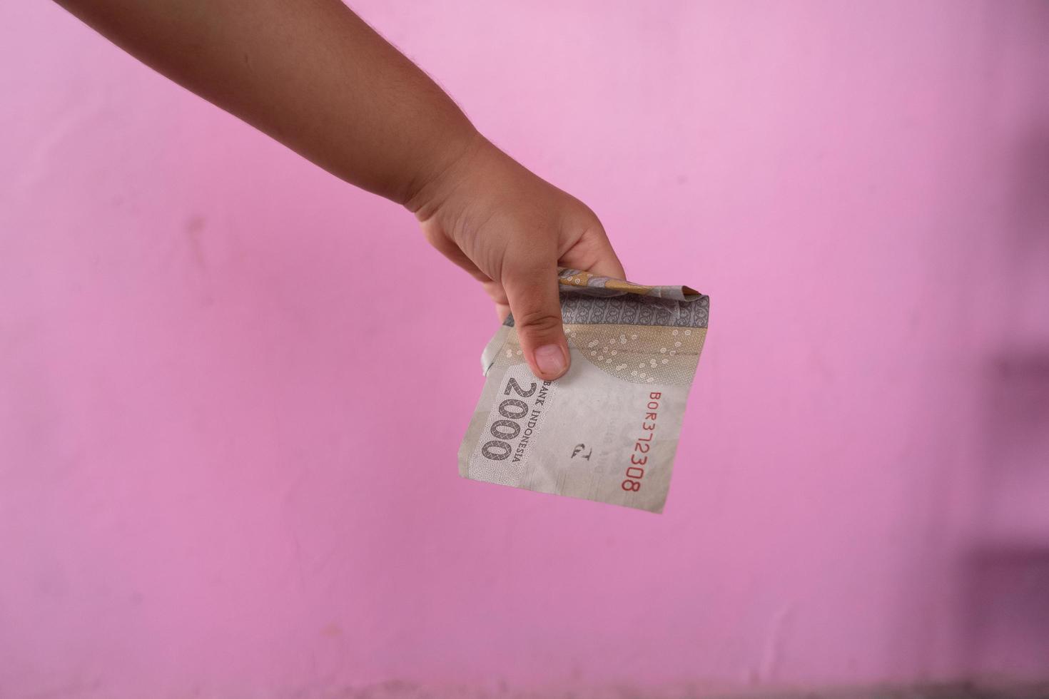 selective focus on the Indonesian two thousand rupiah banknote held by an Asian girl photo