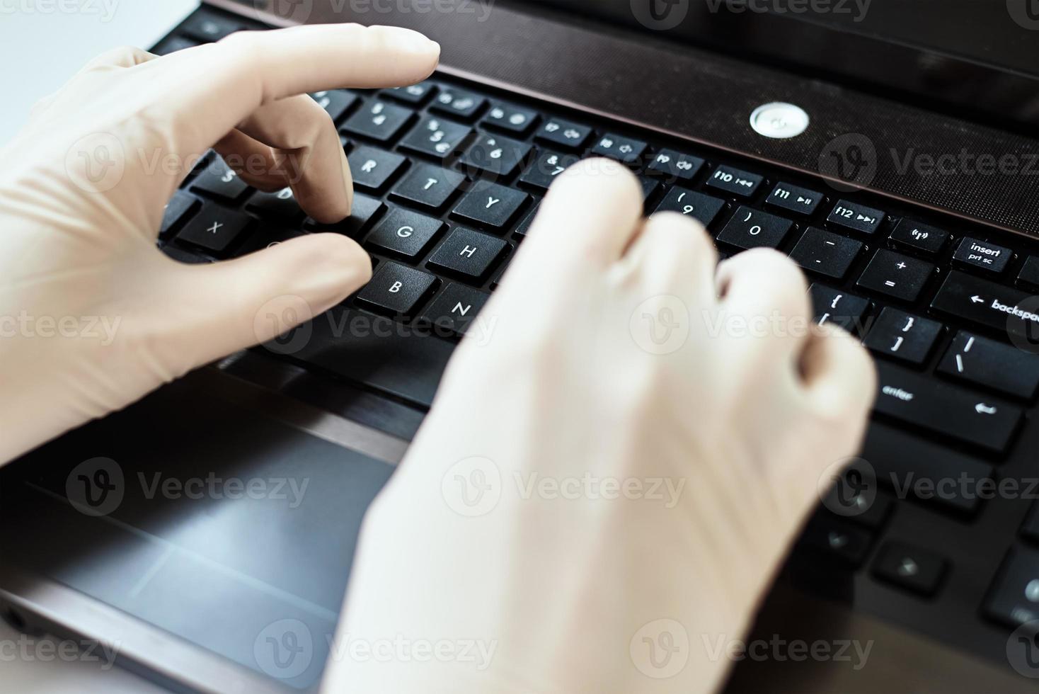 Hands in gloves typing on the laptop keyboard. Virus protection concept photo