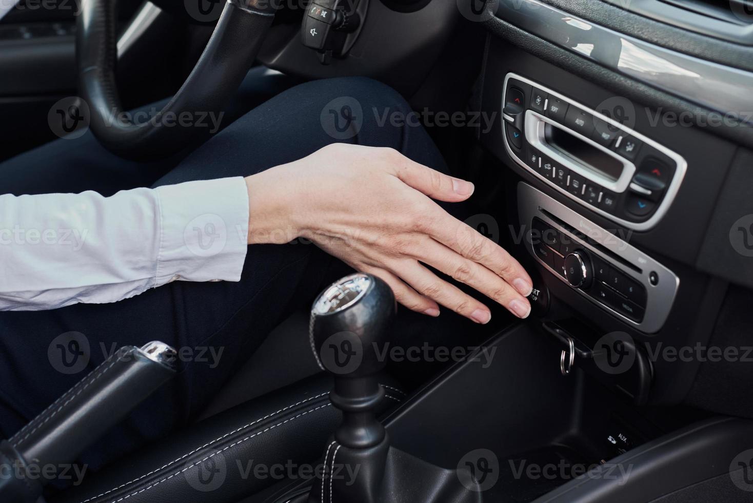 Driver starting car engine with a keyless system. Woman press start button photo