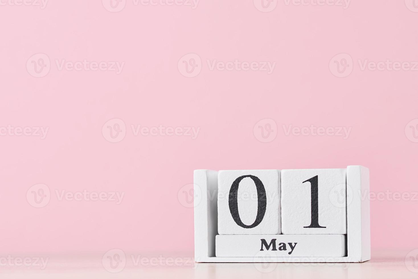 Wooden block calendar with date May 1 on pink background photo