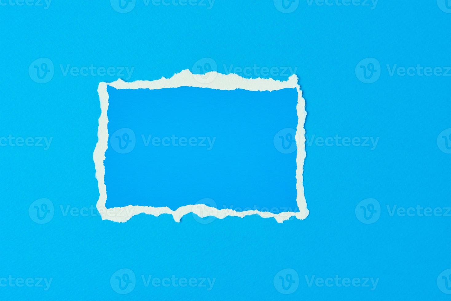 Ripped paper torn edge sheet on a blue background photo