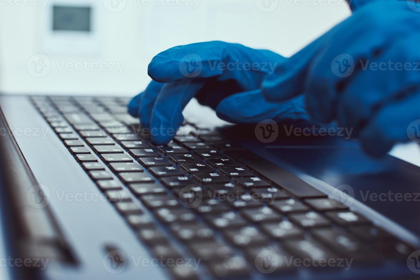 Hand in protective gloves typing on the laptop keyboard photo
