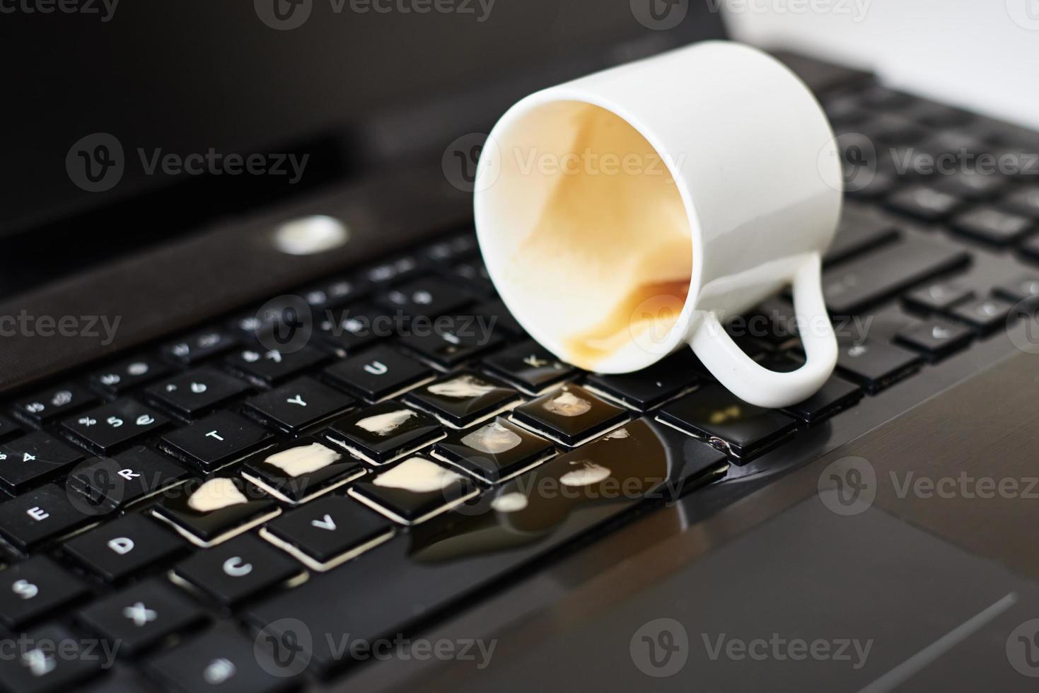 Spill coffee from white cup on the computer laptop keyboard photo