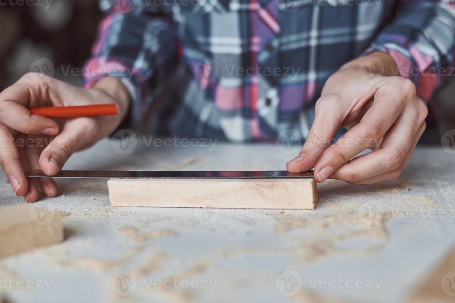 Carpenter hands taking measurement with a pencil of wooden plank photo