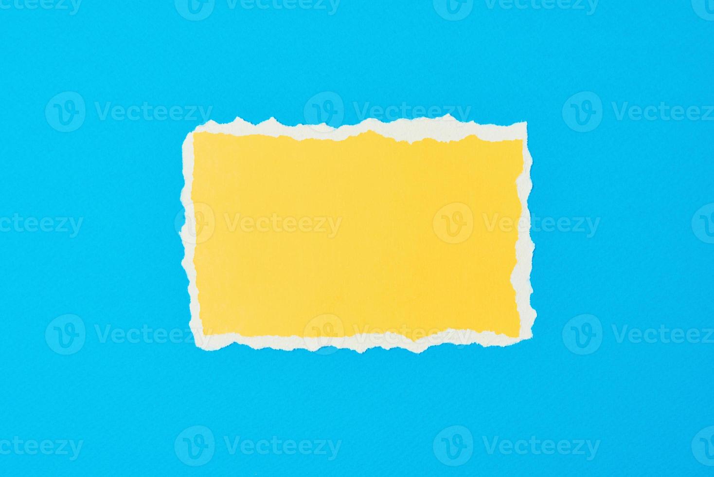 papel amarillo rasgado hoja de borde rasgado sobre un fondo azul foto