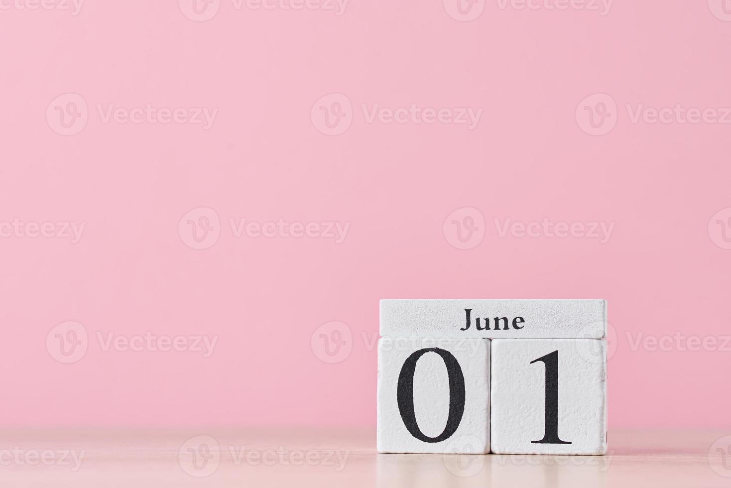 Wooden block calendar with date June 1 on pink background photo