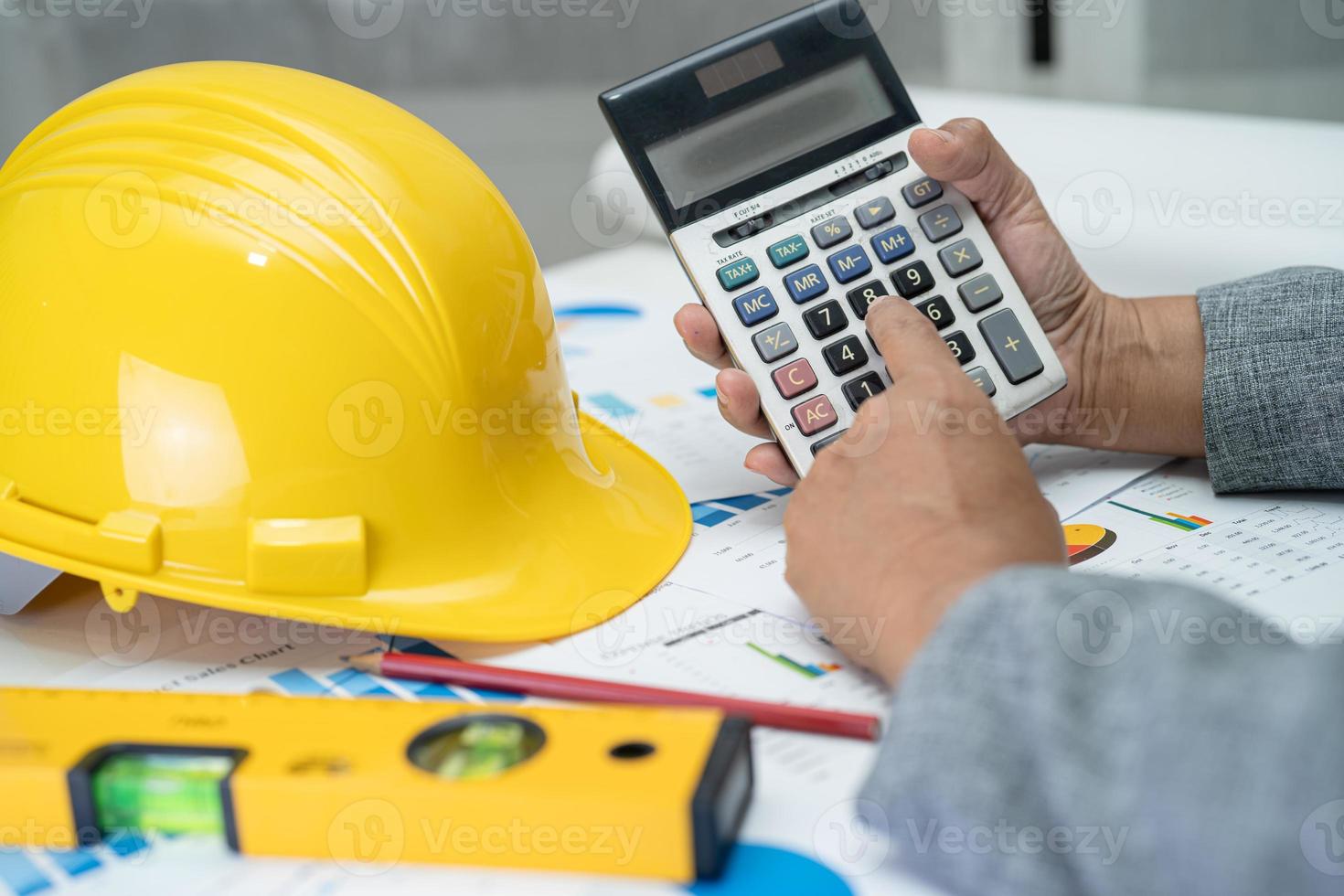 Asian engineer with architectural house plan project blueprint, graph and yellow helmet and engineering construction tools. photo