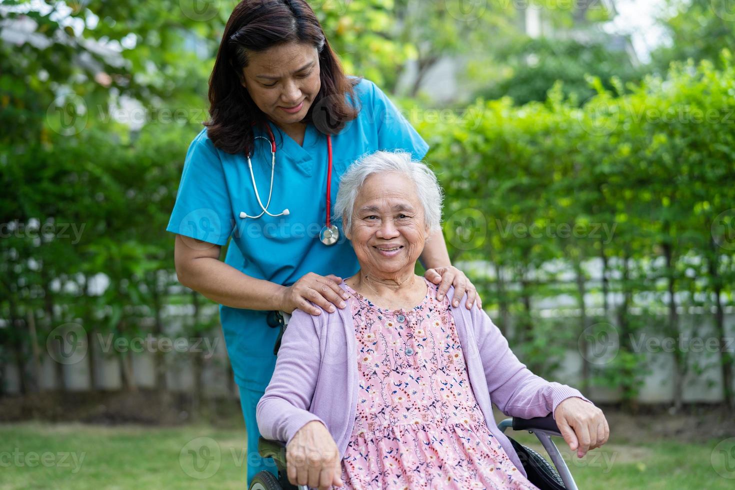 médico cuidador ayuda y cuida a una anciana asiática o anciana paciente sentada en silla de ruedas en un parque en un hospital de enfermería, un concepto médico fuerte y saludable foto