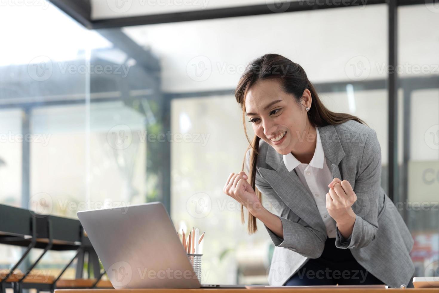 emocionada mujer asiática feliz mirando la pantalla del teléfono, celebrando una victoria en línea, joven asiática muy contenta gritando de alegría, aislada sobre un fondo blanco borroso foto