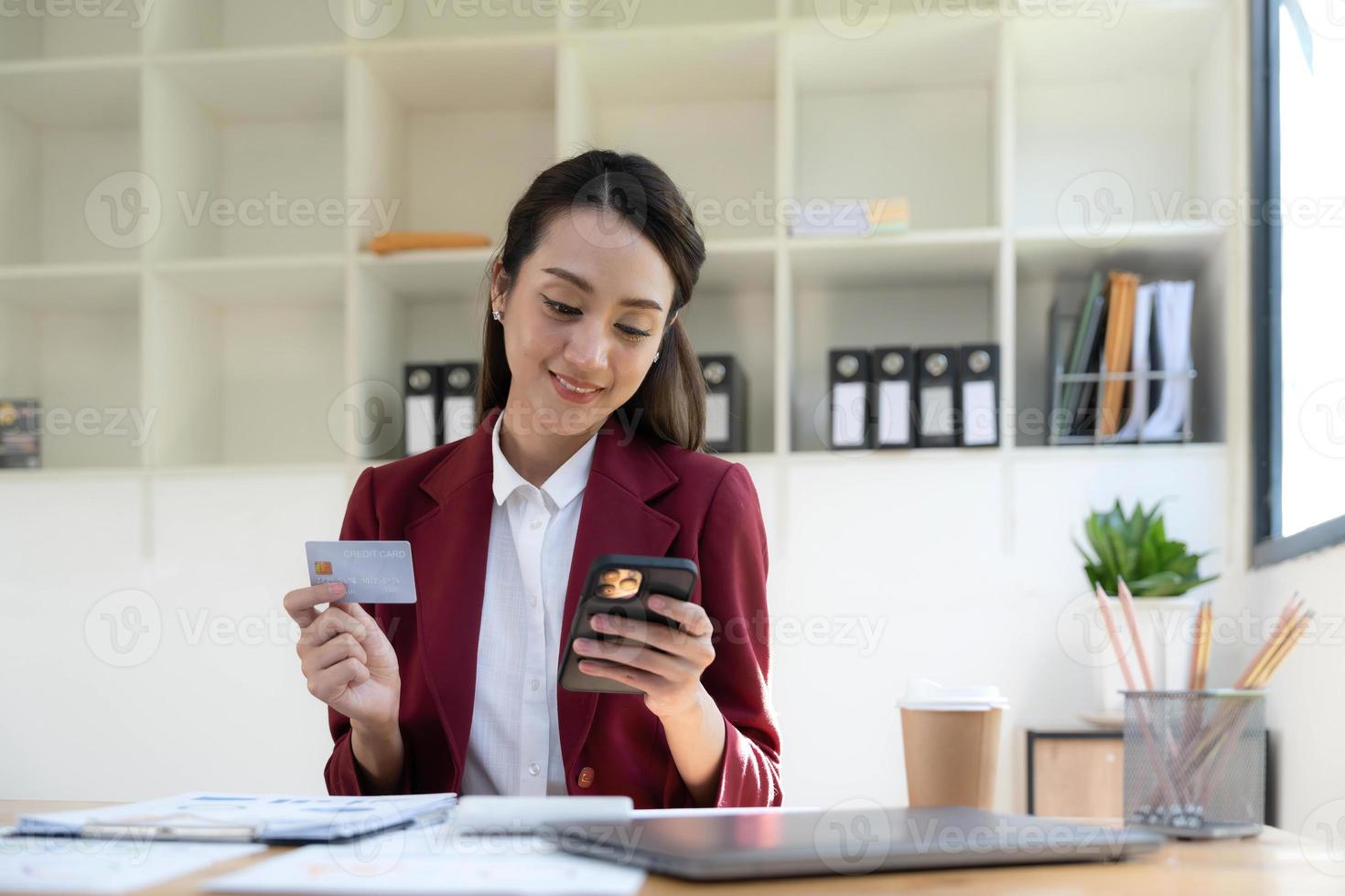 Happy asian Business woman pay online using mobile phone at the office. photo