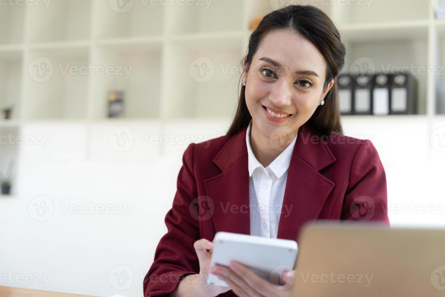 Asian Business woman using calculator and laptop for doing math finance on an office desk, tax, report, accounting, statistics, and analytical research concept photo