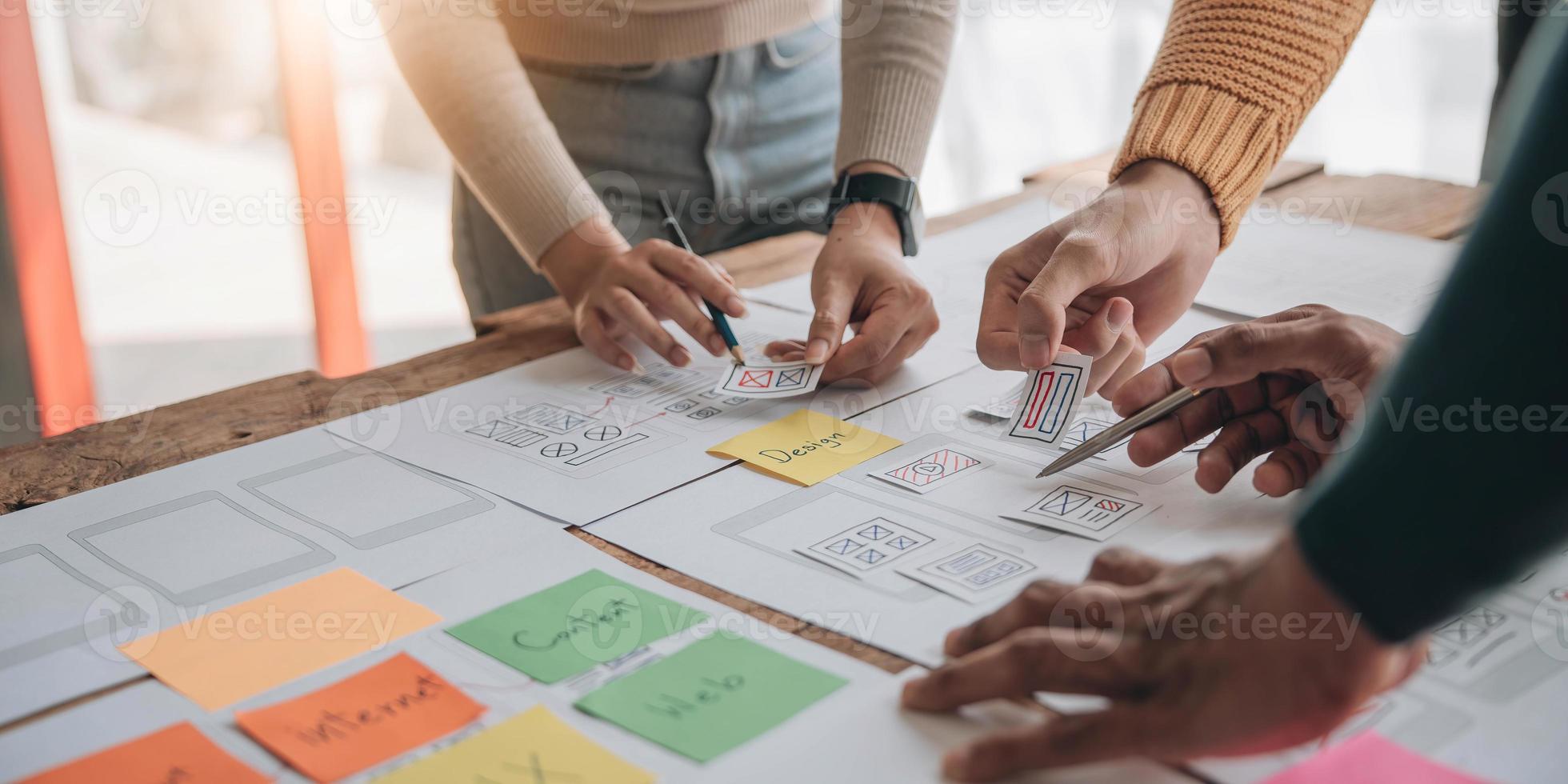 Close up ux developer and ui designer brainstorming about mobile app interface wireframe design on table with customer breif and color code at modern office.Creative digital development agency photo