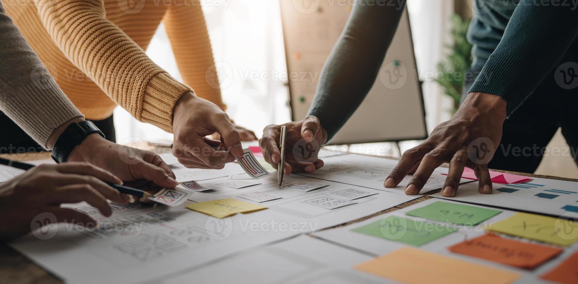 Close up ux developer and ui designer brainstorming about mobile app interface wireframe design on table with customer breif and color code at modern office.Creative digital development agency photo