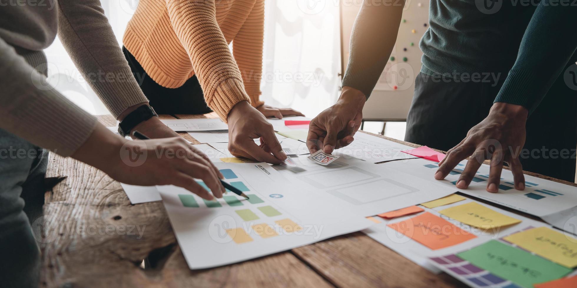 Close up ux developer and ui designer brainstorming about mobile app interface wireframe design on table with customer breif and color code at modern office.Creative digital development agency photo