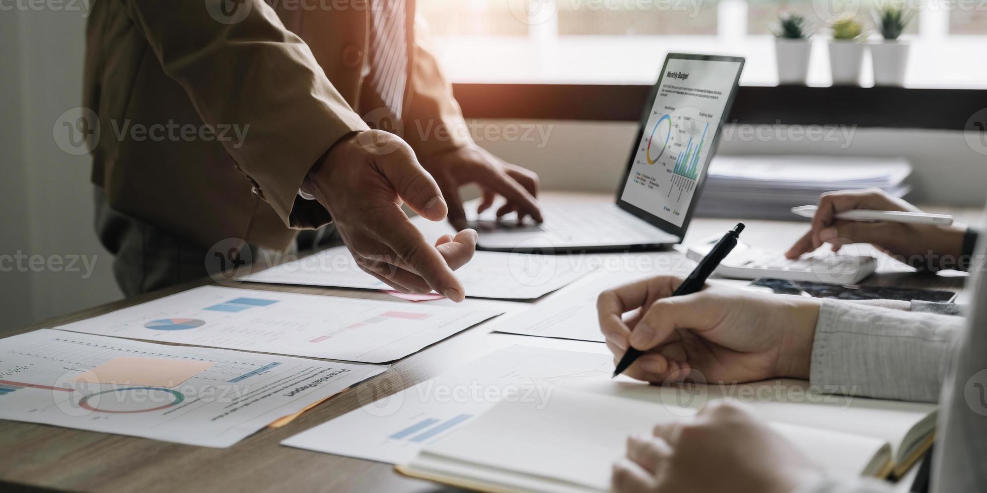 Business People Meeting using laptop computer,calculator,notebook,stock market chart paper for analysis Plans to improve quality next month. Conference Discussion Corporate Concept photo