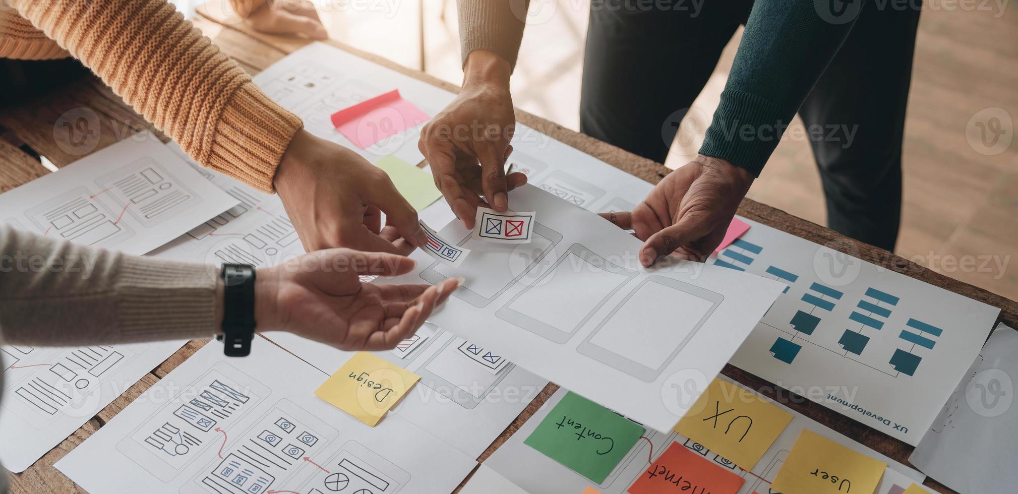 Close up ux developer and ui designer brainstorming about mobile app interface wireframe design on table with customer breif and color code at modern office.Creative digital development agency photo