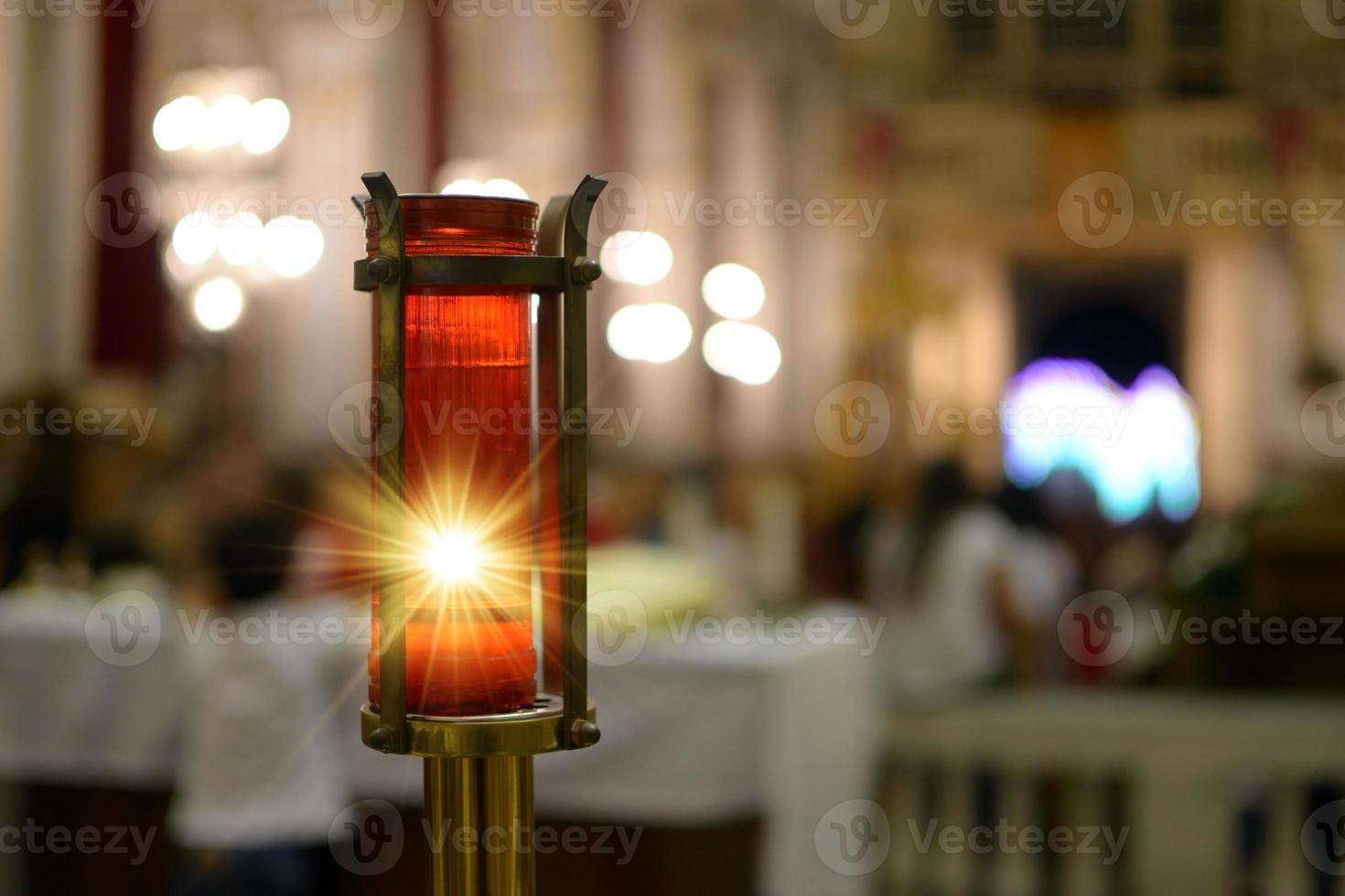 Vela votiva encendida dentro de una iglesia que representa la luz divina. Luz divina. foto