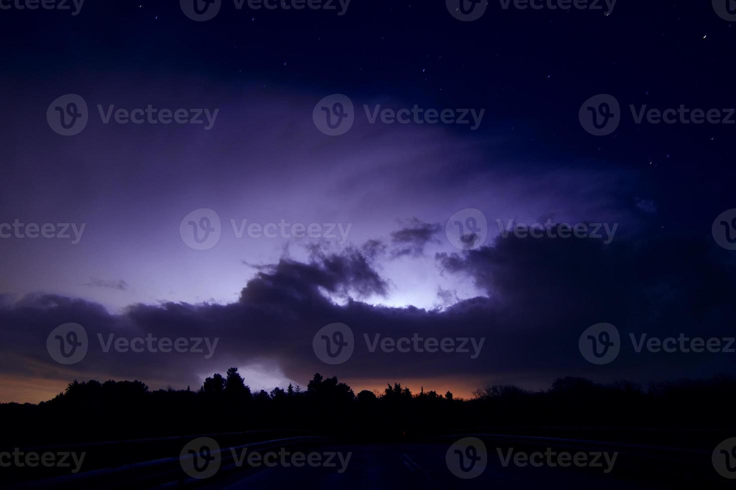 Lightning strikes through storm clouds illuminating the night sky. photo