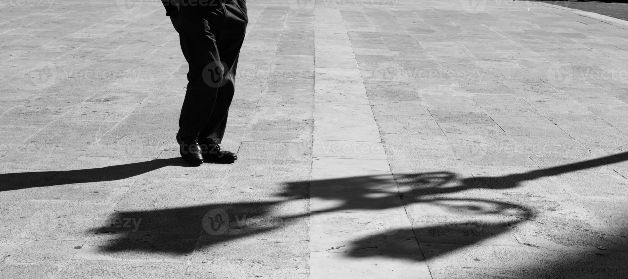 Sicilian man in a square with his hands in his pockets with elongated shadow in black and white.Black and white. Shadow and light, man silhouette photo