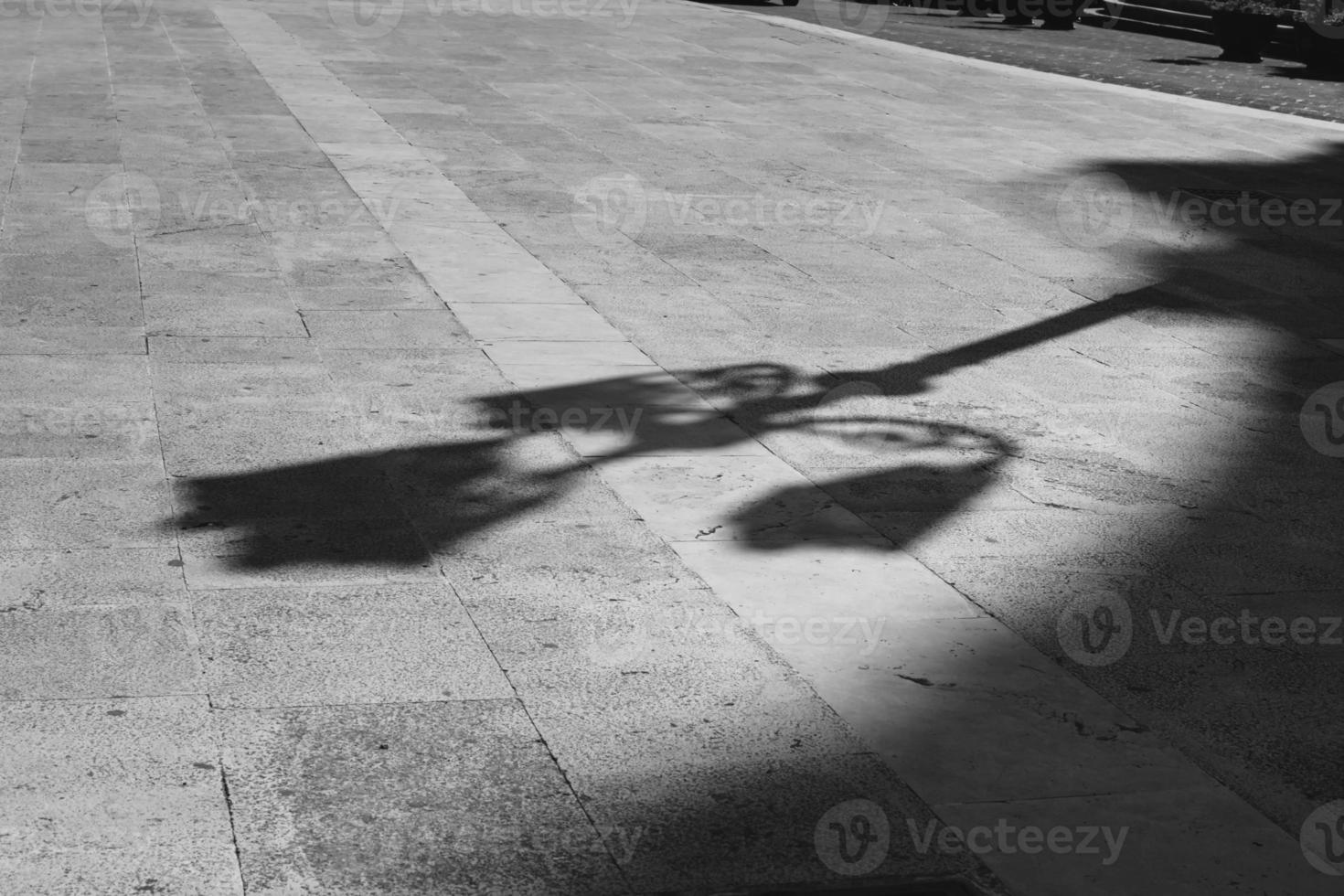 Black and white elongated shadow of a lamppost on a white cobbled square. Black and white. Shadow and light, photo