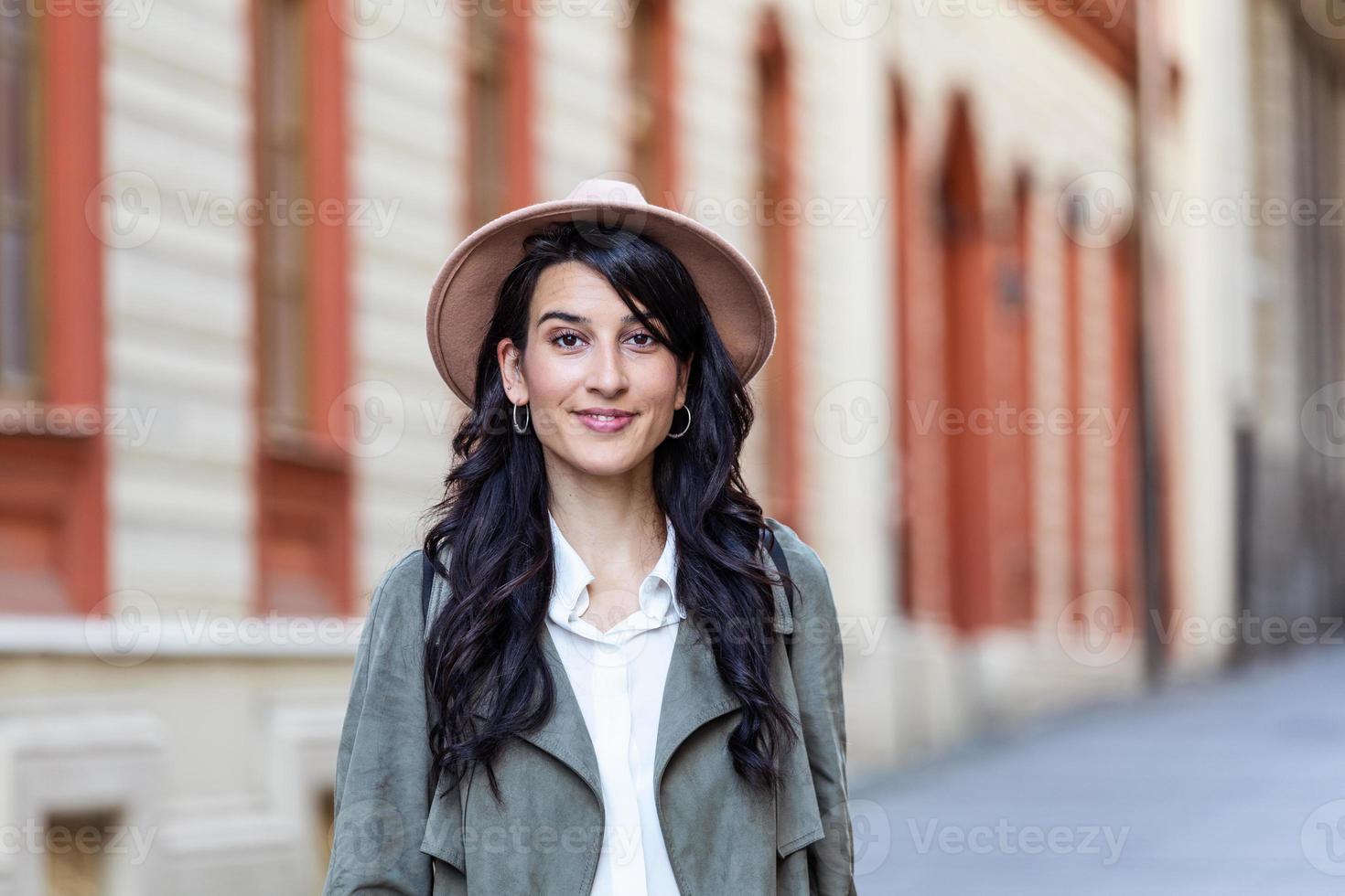 mujer vestida a la moda con un sombrero en las calles de un hermoso pueblo, concepto de compras foto