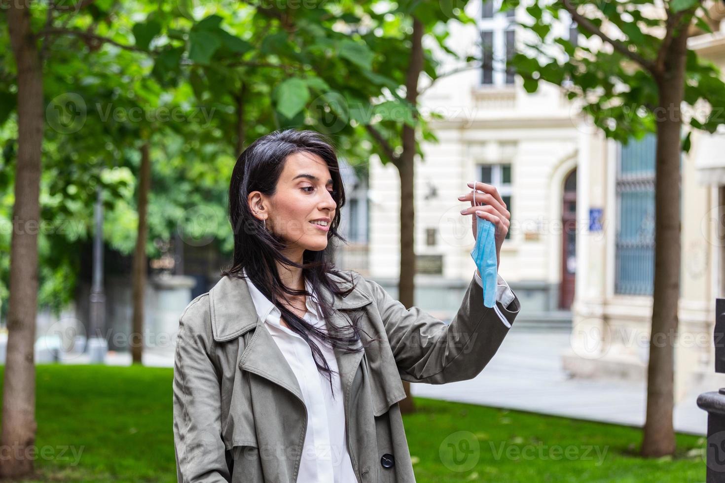 mujer tirando su máscara. joven feliz mirando la máscara médica protectora, quítese la máscara de la cara. fin del concepto de coronavirus pandémico. ncov, covid 19. alergia al polen en primavera foto