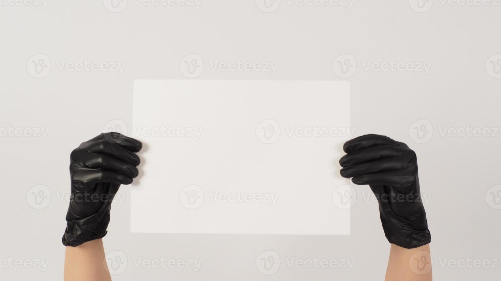 las manos sostienen el papel a4 y usan guantes de látex sobre fondo blanco. foto