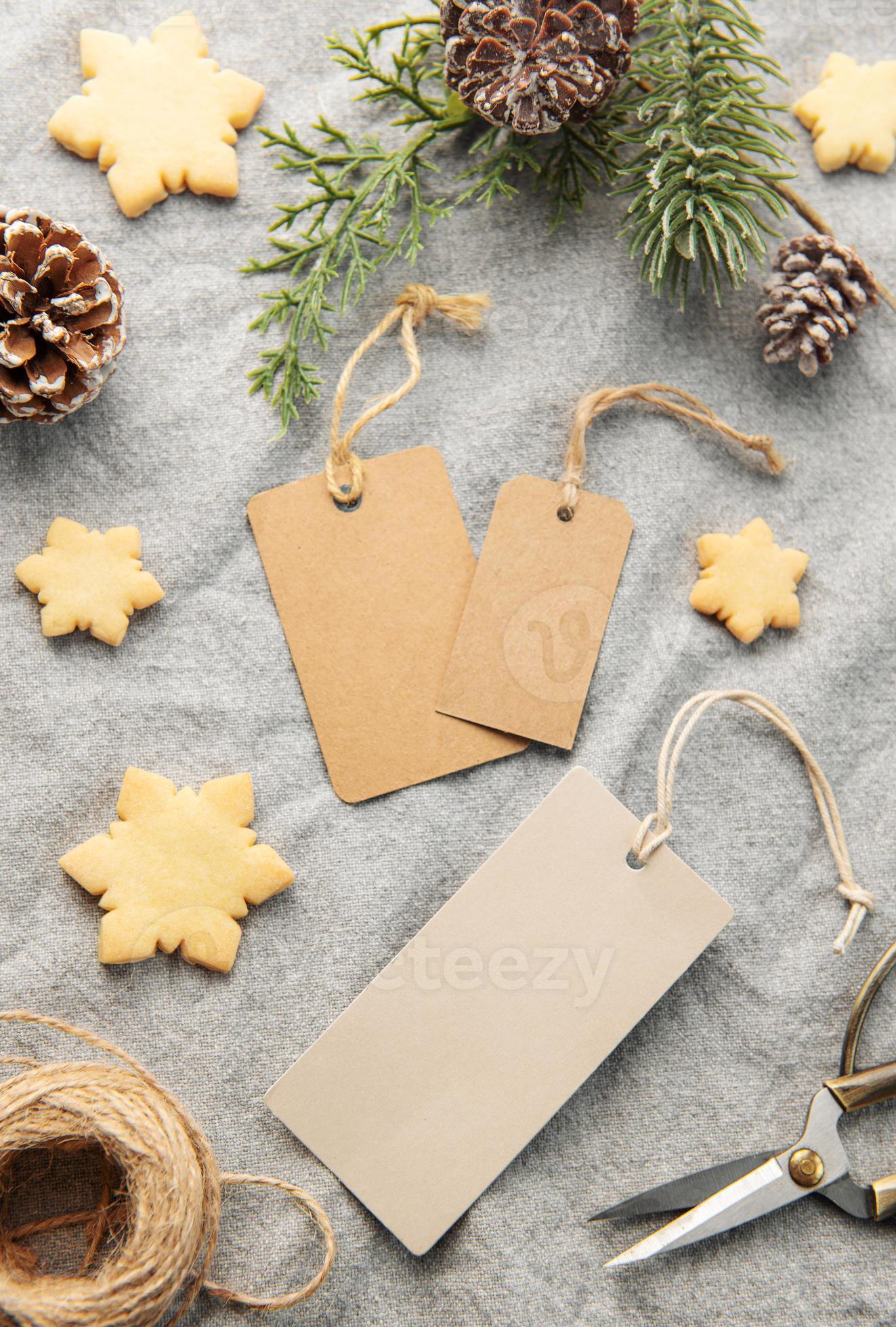 Blank gift tags with pine branch and Christmas cookies on textile  background. Stock Photo by Olena_Rudo