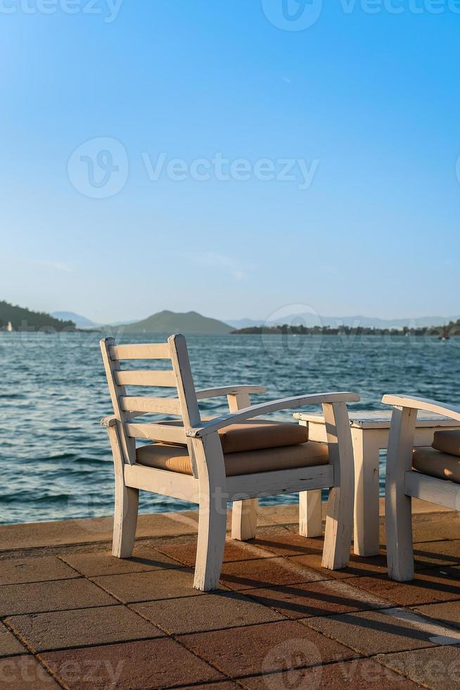 An armchair in a cafe against the background of the sea, evening time, sit in a cafe to admire the sunset. Background idea for holiday advertising. Weekend at sea photo