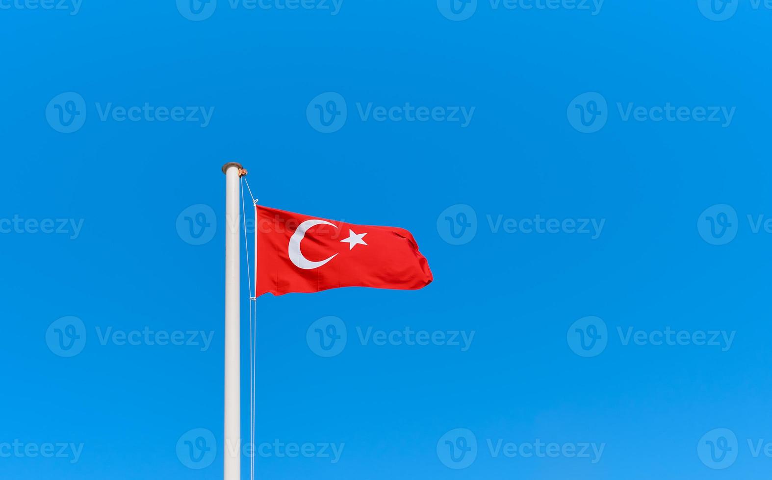 bandera turca en un asta de bandera contra un cielo azul claro con espacio de copia. idea para fondo o papel tapiz foto