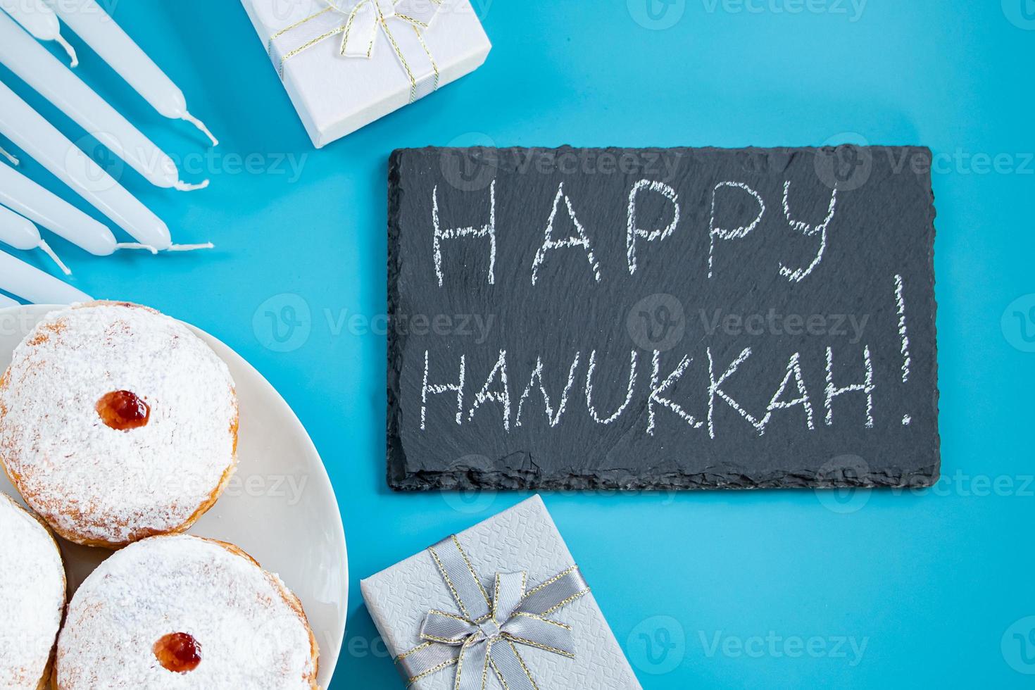 Happy Hanukkah. Jewish dessert sufganiyot donuts on blue background. Symbol of religious Judaism holiday. Inscription on chalk board. photo