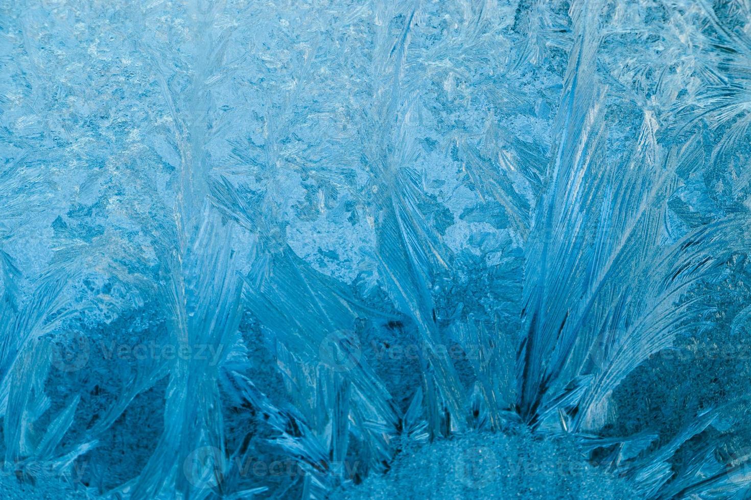 Frosty patterns on glass. Christmas background. Blue ice on winter window. photo